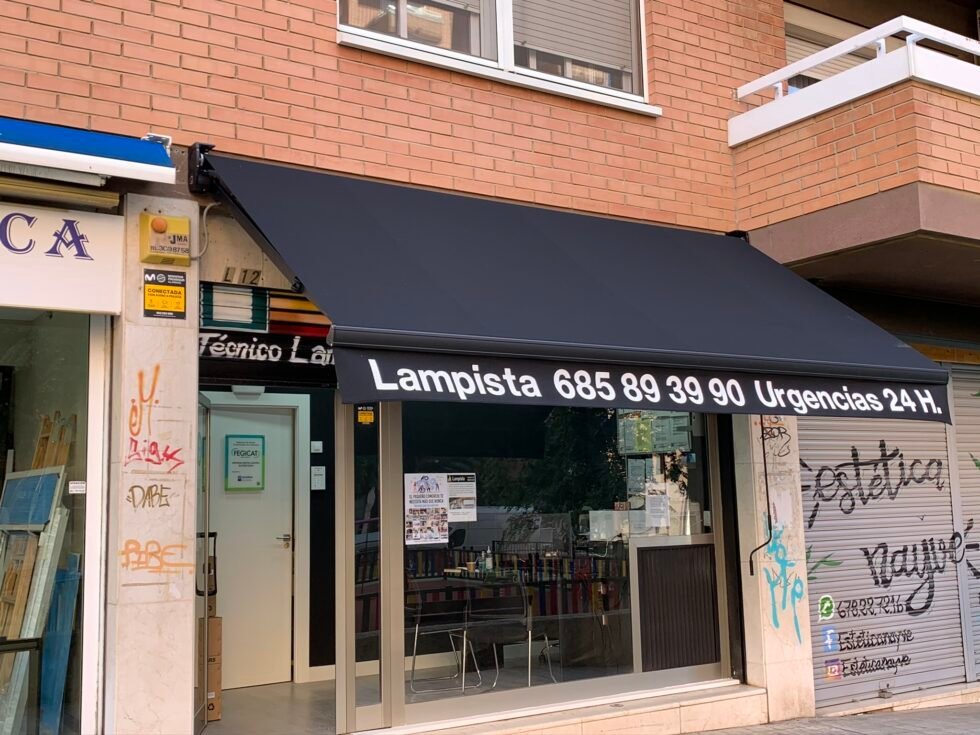 Toldo de comercio con el nombre del negocio rotulado sobre la lona