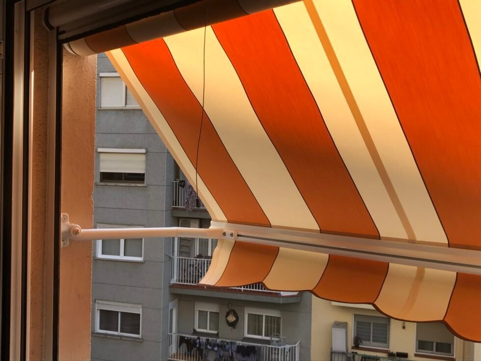 Toldo punto recto de lona clara sobre la ventana de una vivienda